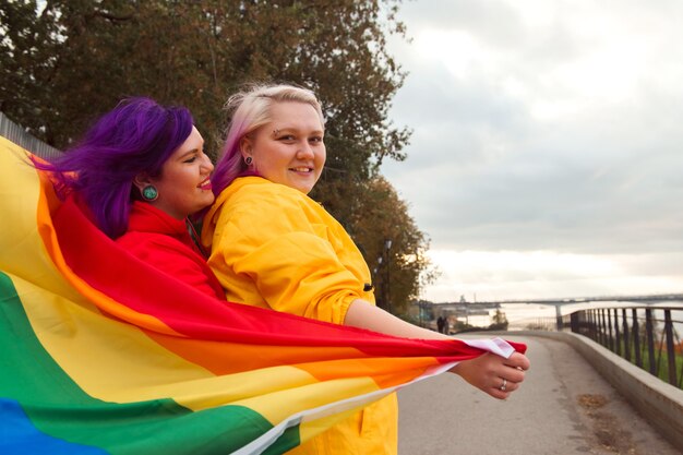 Mulheres jovens felizes segurando a bandeira do orgulho lgbtq