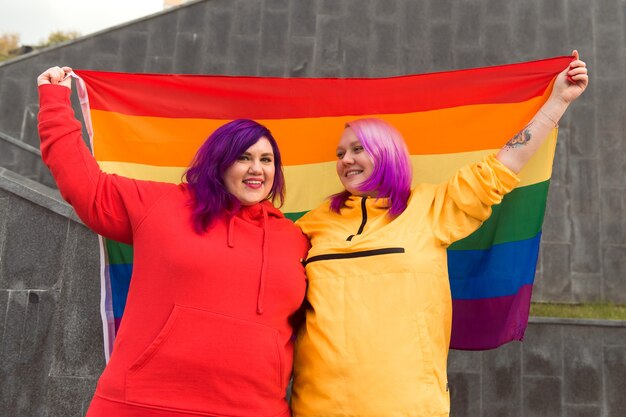 mulheres jovens felizes segurando a bandeira do orgulho lgbtq