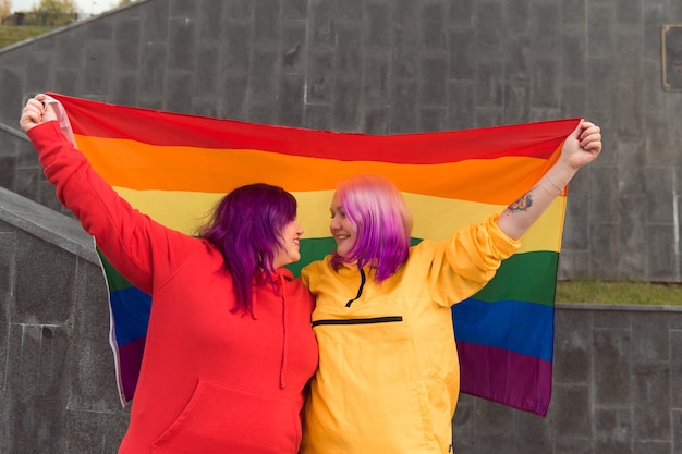 mulheres jovens felizes segurando a bandeira do orgulho lgbtq