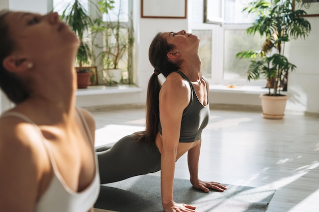 Mulheres jovens praticam ioga fazendo asana em um estúdio de ioga brilhante