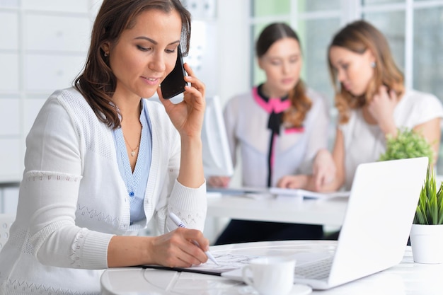 Mulheres jovens sentam-se à mesa e trabalham em um escritório moderno