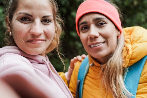 Mulheres jovens tomando uma selfie durante o dia de trekking na floresta de montanha