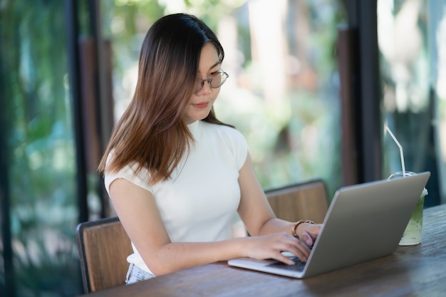 Mulheres jovens trabalhando com o laptop na mesa de madeira do café, conceito de negócio