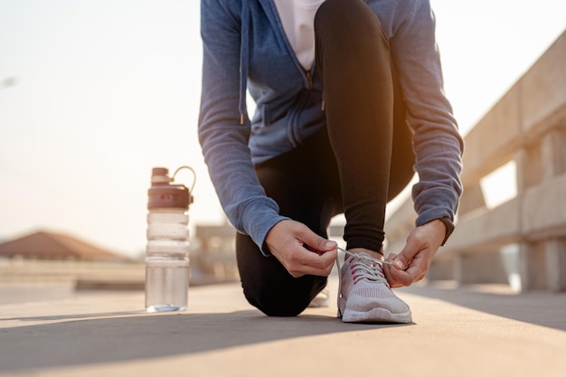 Mulheres jovens usando as mãos para amarrar os sapatos, correndo no treino matinal na cidade. Uma cidade que vive saudável na capital. Exercício, fitness, corrida, corrida, estilo de vida, conceito saudável.