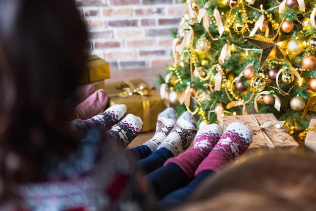 Mulheres jovens usando meias de natal sentadas perto da árvore de natal