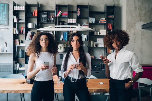 Mulheres jovens, usando, smartphone, e, olhando câmera