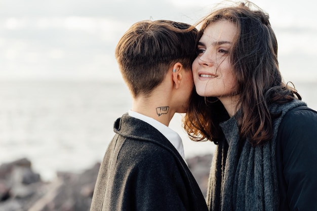 Mulheres lésbicas abraçadas enquanto estão de pé contra o mar