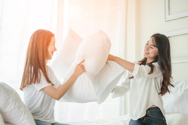 Mulheres lésbicas em lutas de travesseiros no quarto.