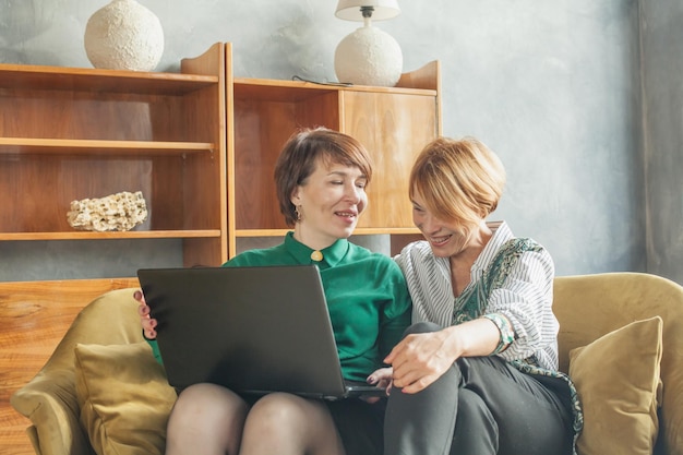 Mulheres maduras casuais com laptop em casa.