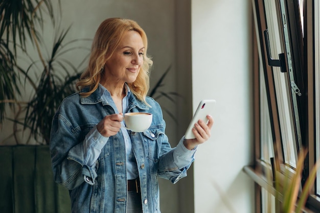 Mulheres maduras usando um telefone em um café