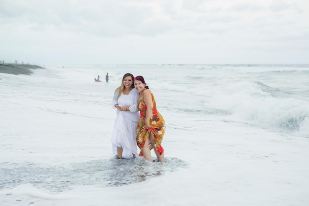 Mulheres, mãe e filha desfrutando de tempo de qualidade na praia. Oceano Pacífico, dia nublado.