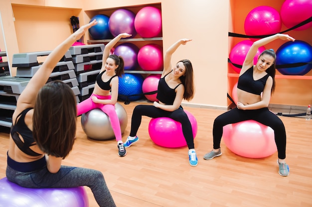 Mulheres malhando com bola de exercício no ginásio