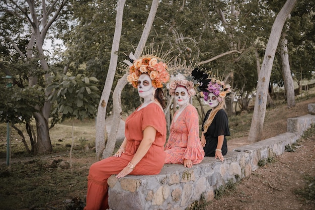 Mulheres maquiadas como catrinas. Dia dos mortos e maquiagem de Halloween. Retrato de grupo ao ar livre de três mulheres