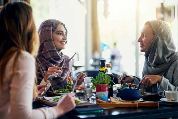 Mulheres muçulmanas amigas e almoçando no restaurante juntas e conversando com sorriso de comida e felicidade Grupo de mulheres islâmicas e comendo brunch com conversa cara feliz e ouvindo com comida no café