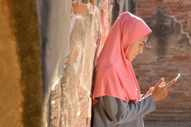 Mulheres muçulmanas usam telefones celulares para entrar em contato com empresas. na velha mesquita em ayutthaya