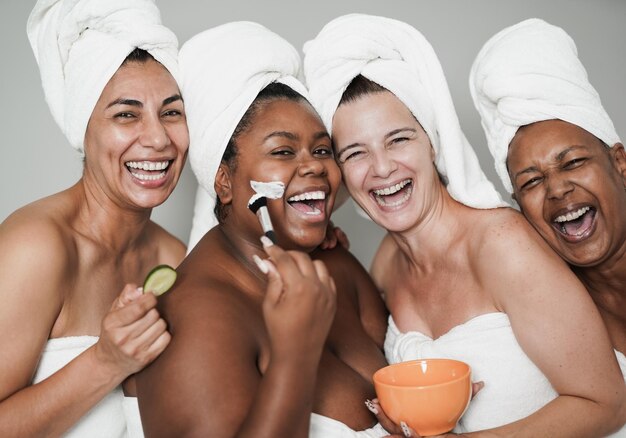 Mulheres multirraciais se divertindo fazendo tratamento de beleza Amigas multigeracionais aproveitam o dia da terapia de cuidados com a pele
