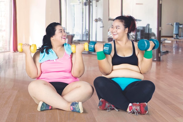 Mulheres obesas fazendo exercícios enquanto estão sentadas na academia