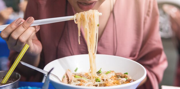 Mulheres que estão apertando o macarrão branco comendo.