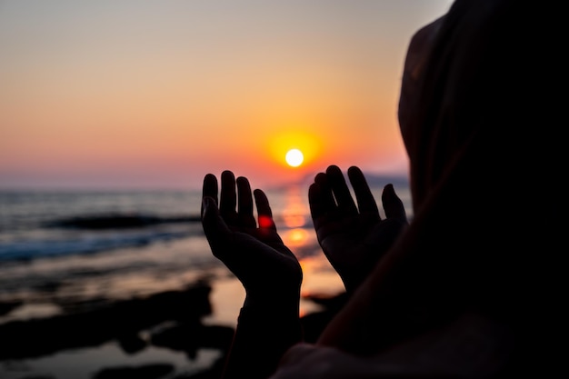 Mulheres rezando para Deus na praia ao pôr do sol