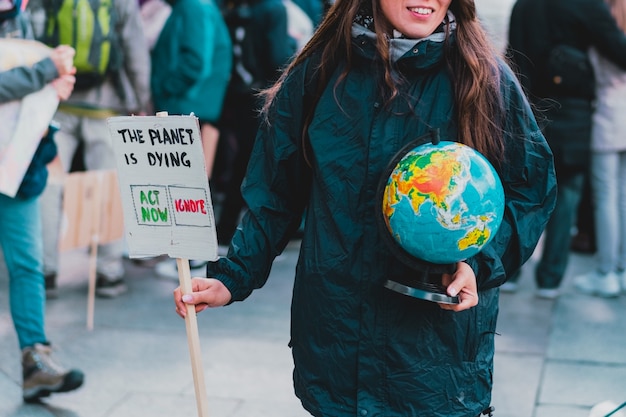 Mulheres seguram um globo terrestre e um banner com a frase 