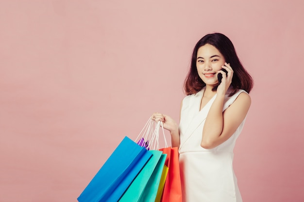 Mulheres segurando sacolas de compras, olhando para o lado em fundo rosa no espaço da cópia