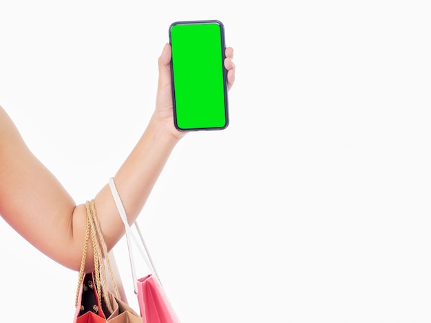 Mulheres segurando smartphone com tela em branco e sacolas de compras na parede branca