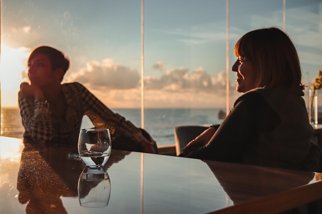 Foto mulheres sentadas na mesa na praia contra o céu