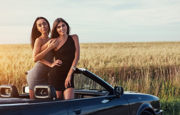 Mulheres sexy, posando em um carro conversível preto