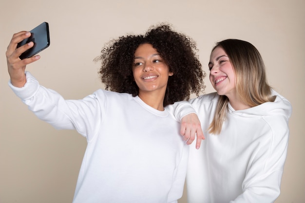 Mulheres sorridentes de tiro médio tomando selfie