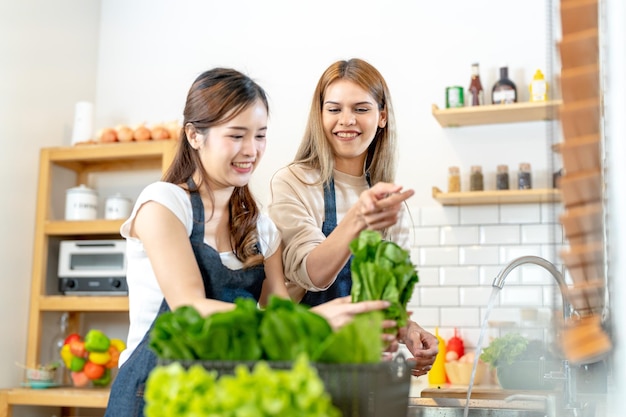 Mulheres sorridentes preparando salada fresca e saudável mulher parada na despensa em uma bela cozinha interior A comida de dieta limpa de produtos e ingredientes locais Mercado fresco