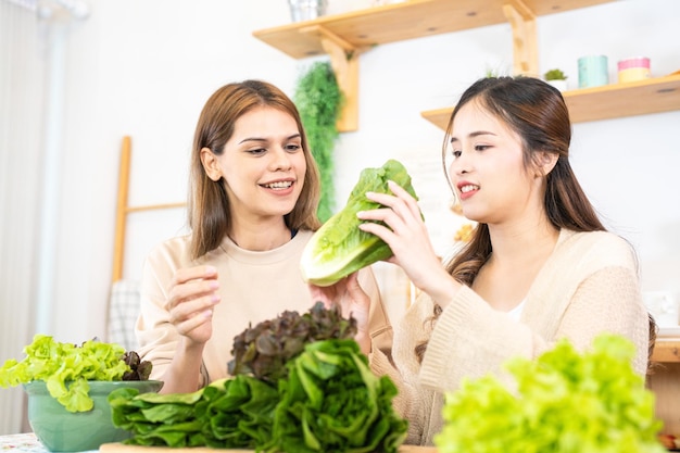 Mulheres sorridentes preparando saladas frescas e saudáveis mulher sentada na despensa em uma bela cozinha interior A comida de dieta limpa de produtos e ingredientes locais Mercado fresco