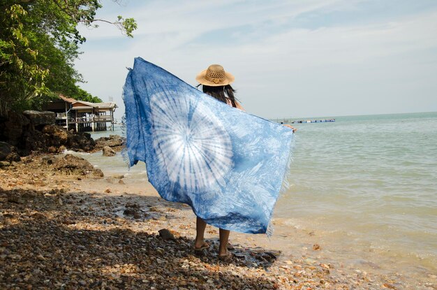 Mulheres tailandesas asiáticas relaxam e jogam xale de tecido índigo tie dye na praia de pedra no mar de andaman e oceano em ko yao noi em phang nga tailândia