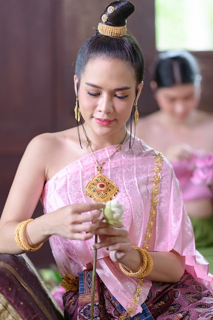 Mulheres tailandesas em trajes tradicionais tailandeses estão decorando flores.