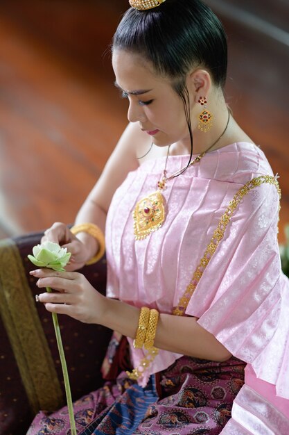 Mulheres tailandesas em trajes tradicionais tailandeses estão decorando flores.