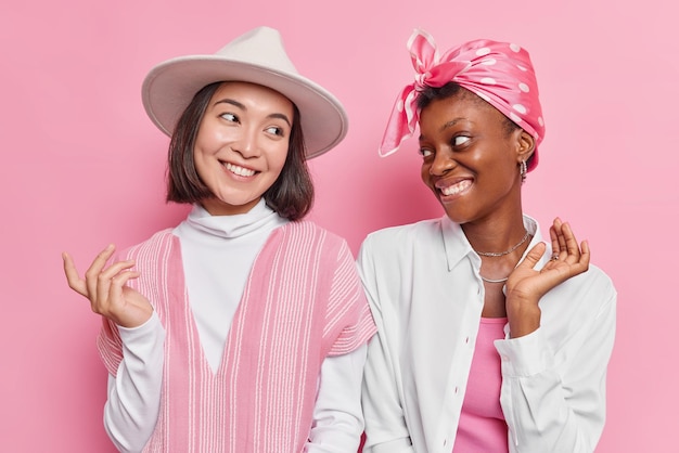 Mulheres têm relacionamentos amigáveis olham com alegria uma para a outra fica um ao lado do outro vestidos com roupas da moda isoladas em rosa. que bom que amigos se encontram