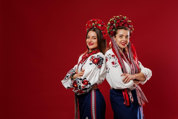 Mulheres ucranianas em roupas étnicas tradicionais e guirlanda vermelha floral em fundo de estúdio viva magenta Vestido nacional bordado chama vyshyvanka Ore pela Ucrânia