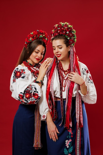 Mulheres ucranianas em roupas étnicas tradicionais e guirlanda vermelha floral em fundo de estúdio viva magenta Vestido nacional bordado chama vyshyvanka Ore pela Ucrânia