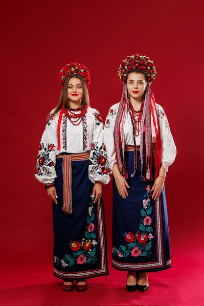 Mulheres ucranianas em roupas étnicas tradicionais e guirlanda vermelha floral em fundo de estúdio viva magenta Vestido nacional bordado chama vyshyvanka Ore pela Ucrânia