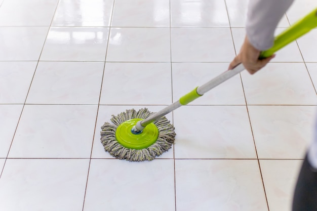 Mulheres usando esfregão, limpando o chão sujo da casa.