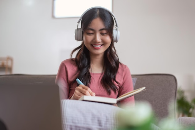 Mulheres usando fone de ouvido para ouvir música e escrever notas no diário no estilo de vida em casa