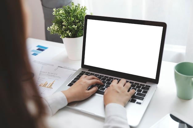 Mulheres usando laptop com tela em branco na mesa no escritório.