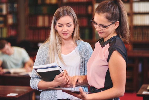 Mulheres usando tablet digital na biblioteca