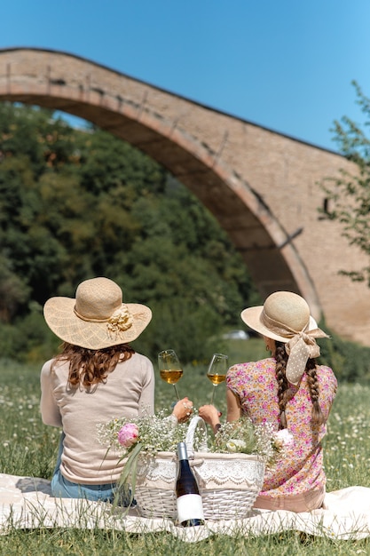 Mulheres verticais irreconhecíveis, sentadas com chapéu de palha, olhando para a paisagem, segurando uma cena rural