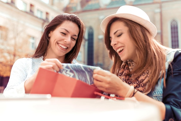 Mulheres viciadas em compras felizes verificando roupas no café