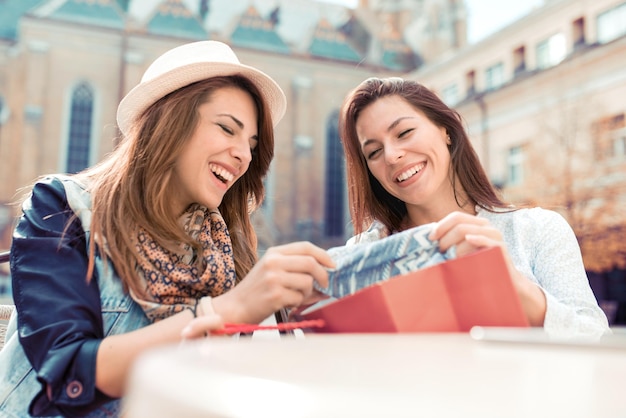 Mulheres viciadas em compras felizes verificando roupas no café