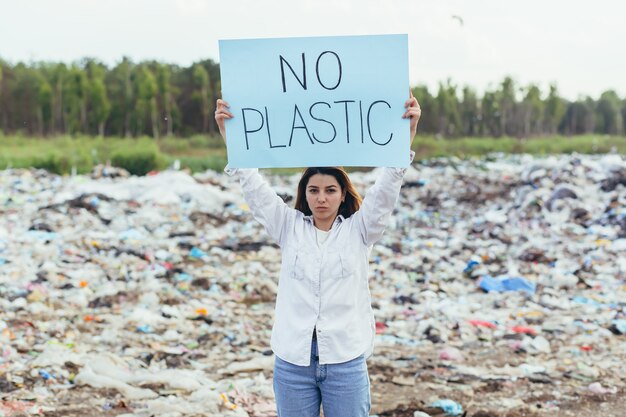 Mulheres voluntárias fazem piquete em aterro sanitário com um pôster sem plástico, ativista luta contra a poluição ambiental