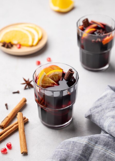 Mulled-Wein mit orangen Äpfeln und Zimt in Gläsern auf einem hellen Hintergrund Das Konzept eines traditionellen warmen Wintergetränks