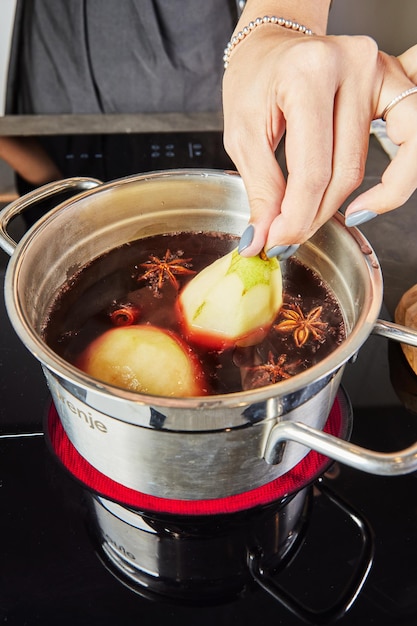 Mulled Wine mit Birnen und Gewürzen in einem Edelstahltopf auf dem Herd