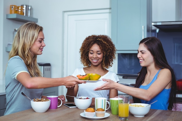 Multi ethnische Freunde, die Platte mit Papaya im Haus halten