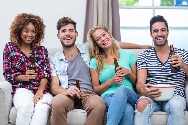 Multi ethnische junge Freunde, die Bier auf Sofa genießen